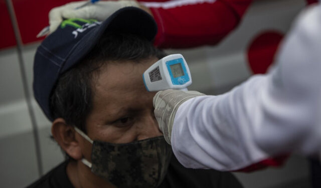 International Red Cross workers check truck drivers pressure and temperature during a blockade at Penas Blancas border between Nicaragua and Costa Rica, in Rivas, Nicaragua, on May 28, 2020. - Thousands of Nicaraguan truckers blocked the country's southern border on Wednesday, in retaliation for the sanitary restrictions imposed by Costa Rica on cargo transportation to contain the spread of the new coronavirus COVID-19. (Photo by Inti OCON / AFP)