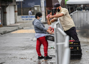 A man delivers bread to a woman at the Santa Cruz neighborhood in Medellin, Colombia on June 6, 2020. - Authorities placed the Santa Cruz neighborhood under strickled lockdown after an outbreak of Covid-19 coronavirus cases. (Photo by JOAQUIN SARMIENTO / AFP)