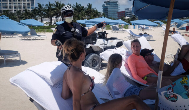A police offices talks to beachgoers as beaches are reopened with restrictions to limit the spread of the coronavirus disease (COVID-19), in Miami Beach, Florida, U.S., June 10, 2020. REUTERS/Marco Bello