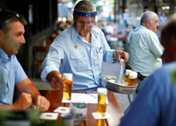 Imagen de archivo de un camarero con un escudo facial sirviendo cervezas a unos clientes en la terraza de un bar en Colonia, Alemania. 21 mayo 2020. REUTERS/Thilo Schmuelgen