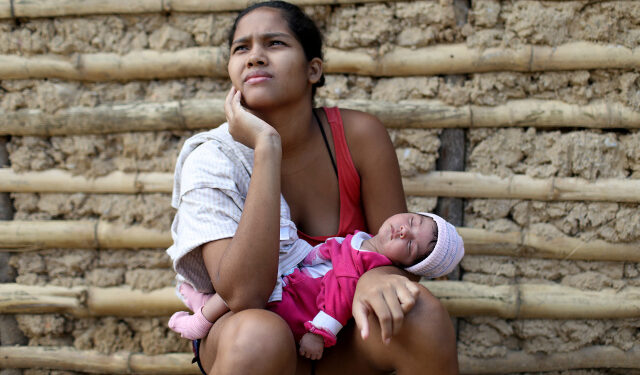 Yuseli Rincón y su bebé de 21 días junto a su casa hecha con barro, palos y láminas metálicas en la municipalidad de Sucre, cerca de Caracas, Venezuela. 12 junio 2020. REUTERS/Manaure Quintero