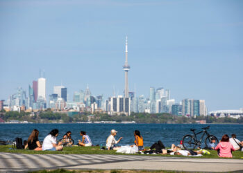 FILE PHOTO: People maintain social distance as they sit at Humber Bay Shores park while the province prepares for more phased re-openings from the coronavirus disease (COVID-19) restrictions in Toronto, Ontario, Canada May 24, 2020. REUTERS/Carlos Osorio/File Photo