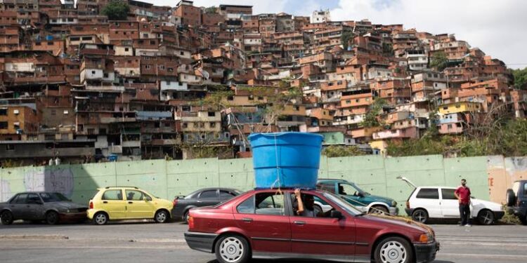 Un auto circula con un enorme recipiente de plástico con agua sobre el techo, en el vecindario humilde de Petare, en Caracas, Venezuela, el 5 de junio de 2020. Se estima que el 86% de los venezolanos reportó problemas con el suministro de agua, incluyendo un 11% que no tiene, según una encuesta realizada por la ONG Observatorio Venezolano de Servicios Públicos entre 4.500 residentes en abril. ARIANA CUBILLOS AP