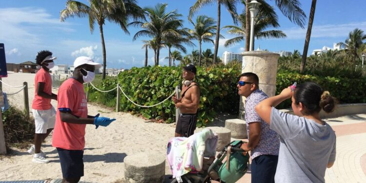 Unos jóvenes revisan las máscaras de unas personas a su llegada el 10 de junio de 2020 a la playa de Miami Beach, Florida. Foto EFE.