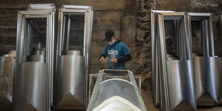 A worker makes a coffin at a factory at Juan de Lurigancho district in Lima, on June 3, 2020 amid the COVID-19 coronavirus pandemic. - While the Peruvian economy has been semi-paralyzed for 80 days due to the pandemic, coffin maker Genaro Cabrera has quadrupled his sales. (Photo by Ernesto BENAVIDES / AFP)