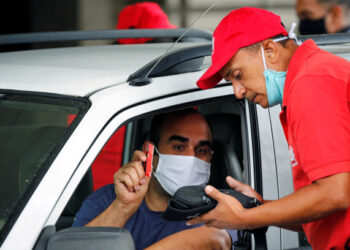 A man wearing a protective face mask pays at a gas station after Venezuela's government launched new fuel pricing system, in Caracas, Venezuela June 1, 2020. REUTERS/Manaure Quintero