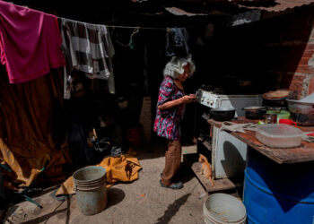 ACOMPAÑA CRÓNICA VENEZUELA CRISIS***AME2816. CARACAS (VENEZUELA), 16/07/2020.- Fotografía fechada el 11 de julio de 2020 de una anciana cocina en su vivienda improvisada en un terreno ocupado en Caracas (Venezuela). De acuerdo con la Encuesta de Condiciones de Vida (Encovi), en Venezuela casi uno de cada diez niños menores de cinco años -unos 166.000- padece algún tipo de desnutrición si se atiende a la relación entre su peso y edad. Y si la relación es entre talla y edad, el dato salta a tres de cada diez, es decir, 639.000 infantes. El número no extraña a los venezolanos, que atraviesan hace más de un lustro por la peor crisis que ha visto el país en su historia moderna. EFE/ Rayner Peña R.