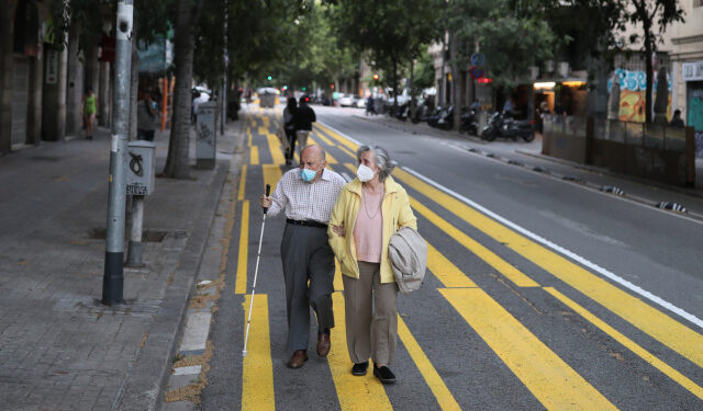 Un matrimonio de ancianos con mascarillas pasea por una franja de color pintada para el uso de peatones a fin de mantener el distanciamiento social, durante el brote de la enfermedad del nuevo coronavirus (COVID-19) en Barcelona, España, el 11 de mayo de 2020. REUTERS/Nacho Doce