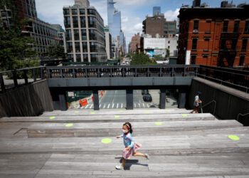 A child wearing a protective face mask plays on a sitting platform painted with social distancing circles on the elevated High Line Park in Manhattan on the first day of the park's re-opening following the outbreak of the coronavirus disease (COVID-19) in New York City, New York, U.S., July 16, 2020. REUTERS/Mike Segar     TPX IMAGES OF THE DAY