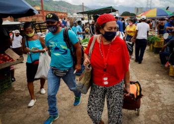 ACOMPAÑA CRÓNICA: CORONAVIRUS VENEZUELA AME4603. CARACAS (VENEZUELA) 27/07/2020.- Personas caminan por el Mercado Mayorista de Coche, el sábado 25 de julio de 2020, en Caracas (Venezuela). Las mascarillas al cuello, a modo de pañuelo, se han convertido en tendencia en Caracas, epicentro de la COVID-19 en Venezuela. Los casi cuatro meses y medio de cuarentena y medidas incumplidas han llevado a los ciudadanos a olvidarse del verdadero peligro del virus, y han convertido a la capital en una ruleta rusa. EFE/RAYNER PEÑA R.