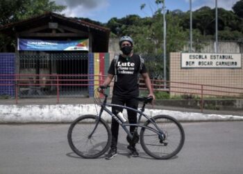 Repartidor de deberes en bicicleta a alumnos de una favela de Brasil. Foto Agencias.