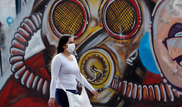 Una mujer con tapabocas camina el pasado jueves 2 de julio del 2020 frente a un grafiti en Bogotá (Colombia). EFE/ Mauricio Dueñas Castañeda
