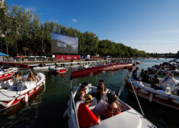 People arrive to watch the film "Le Grand Bain" from boats at the Cinema on the water (Cinema sur l?eau) as a floating cinema with 38 socially-distant electric boats kicks off the Paris Plages summer event along the Bassin de la Villette, in Paris following the outbreak of the coronavirus disease (COVID-19) in France July 18, 2020. REUTERS/Gonzalo Fuentes