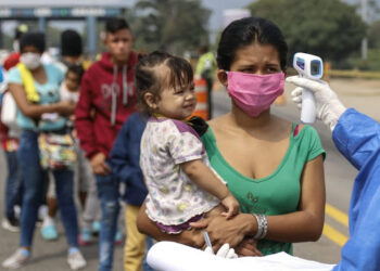 Staffers from the Secretary of Health take the temperature of Venezuelans returning to the country from Colombia, as a preventive measure against the spread of the coronavirus -COVID19- at the Simon Boliviar International Bridge, in Cucuta, Colombia-Venezuela border, on April 4, 2020. - Since the first case of COVID-19 was detected last March 6, Colombia has reported 1,406 people infected and 32 dead. (Photo by Schneyder MENDOZA / AFP)