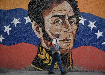 A man wearing a face mask walks past a mural depicting South American independence hero Simon Bolivar in Caracas on April 17, 2020, amid the novel coronavirus (COVID-19) outbreak. - The health emergency due to the new coronavirus in Venezuela reinforced Nicolas Maduro's internal control and neutralized Juan Guaido, making him more dependant on his international allies, just when the opposition tried to reactivate its offensive against the socialist government. (Photo by Federico Parra / AFP) (Photo by FEDERICO PARRA/AFP via Getty Images)