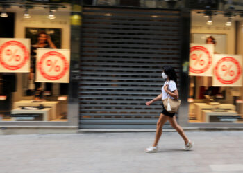 FOTO DE ARCHIVO: Una mujer con mascarilla camina frente a una tienda cerrada en Lleida, Cataluña, España, el 13 de julio de 2020. REUTERS/Nacho Doce