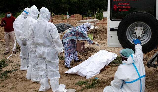 A relative performs the last rites before the burial of a woman who died due to coronavirus disease (COVID-19), at a graveyard, in New Delhi, India, August 7, 2020. REUTERS/Adnan Abidi