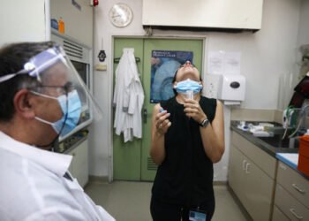 A woman rinses her mouth with a saline wash during a demonstration for Reuters of ongoing clinical trials led by Sheba Medical Center and Israeli firm Newsight Imaging, in which they say a newly developed saliva test aims to determine in less than a second whether or not you are infected with the coronavirus disease (COVID-19), at Tel Hashomer in Ramat Gan, Israel August 13, 2020. REUTERS/Ammar Awad