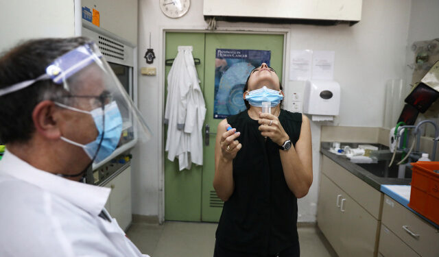 A woman rinses her mouth with a saline wash during a demonstration for Reuters of ongoing clinical trials led by Sheba Medical Center and Israeli firm Newsight Imaging, in which they say a newly developed saliva test aims to determine in less than a second whether or not you are infected with the coronavirus disease (COVID-19), at Tel Hashomer in Ramat Gan, Israel August 13, 2020. REUTERS/Ammar Awad