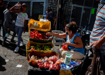 AME1304. CARACAS (VENEZUELA), 21/05/2020.- Una mujer organiza un puesto informal de venta de frutas y verduras, el 16 de mayo de 2020, en Caracas (Venezuela). Venezuela cumplirá la próxima semana un mes haber puesto en marcha un nuevo mecanismo de control de precios, una medida que, por ahora, ha defraudado las expectativas del Gobierno de Nicolás Maduro, que esperaba el freno de la inflación, y de los analistas económicos, que vaticinaron una severa escasez. EFE/ Rayner Peña