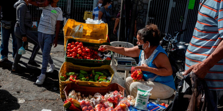 AME1304. CARACAS (VENEZUELA), 21/05/2020.- Una mujer organiza un puesto informal de venta de frutas y verduras, el 16 de mayo de 2020, en Caracas (Venezuela). Venezuela cumplirá la próxima semana un mes haber puesto en marcha un nuevo mecanismo de control de precios, una medida que, por ahora, ha defraudado las expectativas del Gobierno de Nicolás Maduro, que esperaba el freno de la inflación, y de los analistas económicos, que vaticinaron una severa escasez. EFE/ Rayner Peña