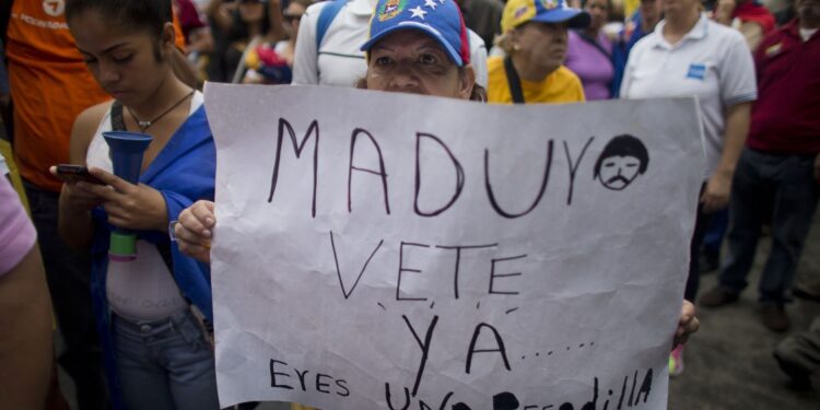 A woman holds a sign with a message that reads in Spanish: "Maduro leave already......you are a nightmare!" during an opposition march in Caracas, Venezuela, Saturday, May 14, 2016. The protesters are demanding that electoral officials accelerate the certification of the petition signatures that would kick off a recall of President Nicolas Maduro. (AP Photo/Ariana Cubillos)