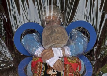 Maria Hernandez, 38, (top) embraces her aunt through a transparent curtain at a Hogar Jardin de Los Abuelitos nursing home in San Salvador on September 11, 2020, amid the new coronavirus pandemic. - According to geriatrician Luis Bermudes, the use of a kind of curtain that allows the elderly guests to be hugged by their relatives without the risk of being infected from COVID-19 is a measure to avoid depression and anxiety. (Photo by Yuri CORTEZ / AFP)