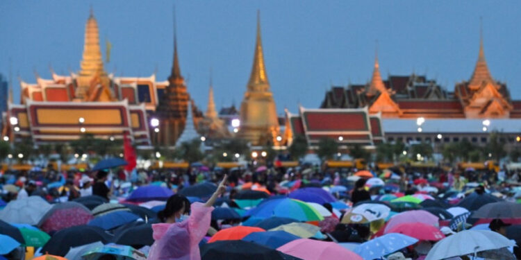 Anti-government protesters gather in Sanam Luang during a pro-democracy rally in Bangkok on September 19, 2020, as the Grand Palace is seen in the background. - Pro-democracy protesters took to the streets of Bangkok on September 19 as a rally expected to draw tens of thousands of people kicked off calling for PM Prayut Chan-O-Cha to step down and demanding reforms to the monarchy. (Photo by Mladen ANTONOV / AFP)