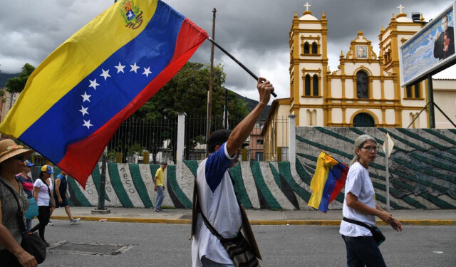 Venezuela's opposition supporters march with a Venezuelan national flag from the UN development program headquarters to the Military Counterintelligence General Directorate (DGCIM) headquarters in Caracas on July 5, 2019, during the anniversary of the Venezuelan Independence. (Photo by Yuri CORTEZ / AFP)