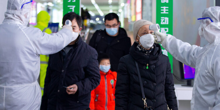 This photo taken on February 18, 2020 shows passengers having their temperature taken as a preventive measure against the COVID-19 coronavirus at a train station in Nanjing, in China's eastern Jiangsu province. - The death toll from China's new coronavirus epidemic jumped past 2,000 on February 19 after 136 more people died, with the number of new cases falling for a second straight day, according to the National Health Commission. (Photo by STR / AFP) / China OUT