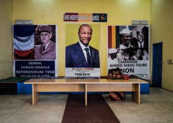 28 February 2020, Guinea, Conakry: A woman sits at a desk in front of election posters. Guinea's President Alpha Conde has postponed the controversial constitutional referendum and parliamentary election scheduled on 01 March 2020. Photo: Sadak Souici/Le Pictorium Agency via ZUMA/dpa