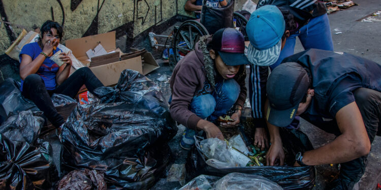 Families salvage food scraps from garbage bags in downtown Caracas, Venezuela, Feb. 10, 2017. A recent report by the United Nations and the Pan American Health Organization found that 1.3 million people who used to be able to feed themselves in Venezuela have had difficulty doing so since the economic crisis began three years ago. (Meridith Kohut/The New York Times) 
CONTACTO
