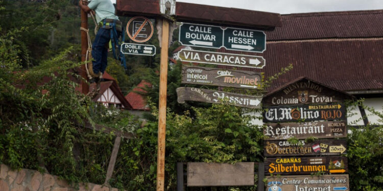 A worker climbs a pole in Colonia Tovar, Tovar Municipality, Aragua state, Venezuela, on November 13, 2020. - Colonia Tovar (Aragua state, center), a town of 21,000 inhabitants famous among Venezuelans for its traditional Bavarian style houses with reddish gabled roofs, lives off tourism and agriculture. The first activity  halted due to the coronavirus, with a quarantine that prevented for months that visitors arrived, and the second was hit by the shortage of fuel that paradoxically punishes this country, once an oil power. (Photo by Cristian Hernandez / AFP)