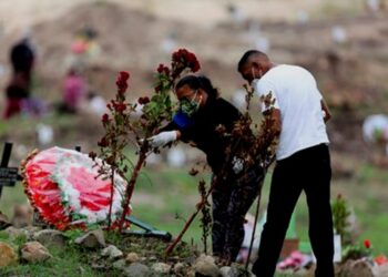 Una pareja visita la tumba de un familiar hoy, en el Parque Memorial Jardín de los Ángeles, cementerio que la Alcaldía de Tegucigalpa dispuso para enterrar a víctimas de la covid-19, en Tegucigalpa (Honduras). EFE/Gustavo Amador.