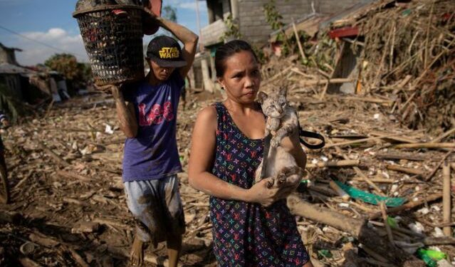 Una mujer carga a su gato en una aldea sumergida tras las inundaciones causadas por el tifón Vamco, en Rodríguez, provincia de Rizal, Filipinas, 14 noviembre 2020.
REUTERS/Eloisa Lopez