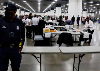 A Detroit Police officer stands guard as Detroit election workers work on counting absentee ballots for the 2020 general election at TCF Center on November 4, 2020 in Detroit, Michigan. - President Donald Trump and Democratic challenger Joe Biden are battling it out for the White House, with polls closed across the United States -- and the American people waiting for results in key battlegrounds still up for grabs. (Photo by JEFF KOWALSKY / AFP) (Photo by JEFF KOWALSKY/AFP via Getty Images)