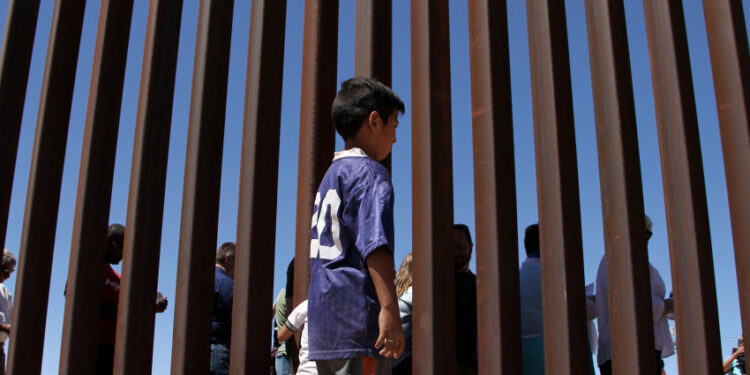 A boy from the Anapra area observes a binational prayer performed by a group of religious presbyters by migrants on the border wall between Ciudad Juarez, Chihuahua state, Mexico and Sunland Park, New Mexico, US, on May 3, 2018. (Photo by Herika Martinez / AFP)        (Photo credit should read HERIKA MARTINEZ/AFP via Getty Images)