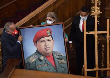 First Lady Cilia Flores, center, and Diosdado Cabello, president of the Constitutional Assembly, carry a portrait of late Venezuelan President Hugo Chavez into the chamber of the National Assembly, as the ruling socialist party prepares to assume the leadership of Congress in Caracas, Venezuela, Tuesday, Jan. 5, 2021. Ruling party allies swept legislative elections last month boycotted by the opposition. (AP Photo/Matias Delacroix)