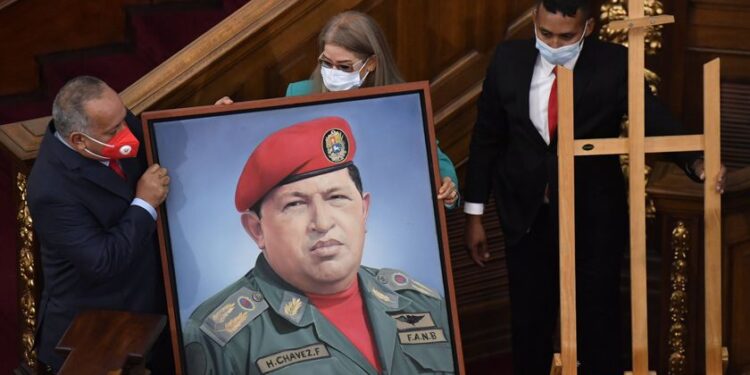 First Lady Cilia Flores, center, and Diosdado Cabello, president of the Constitutional Assembly, carry a portrait of late Venezuelan President Hugo Chavez into the chamber of the National Assembly, as the ruling socialist party prepares to assume the leadership of Congress in Caracas, Venezuela, Tuesday, Jan. 5, 2021. Ruling party allies swept legislative elections last month boycotted by the opposition. (AP Photo/Matias Delacroix)