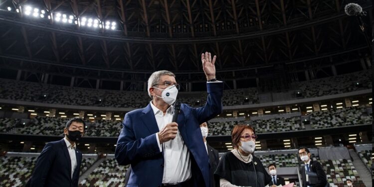 El presidente del Comité Olímpico Internacional Thomas Bach, con una mascarilla, saluda a la prensa en el Estadio Nacional, sede principal de los Juegos Olímpicos de Tokio 2020 que fueron aplazados a julio de 2021, el martes 17 de noviembre de 2020. (Behrouz Mehri/Pool Foto vía AP)