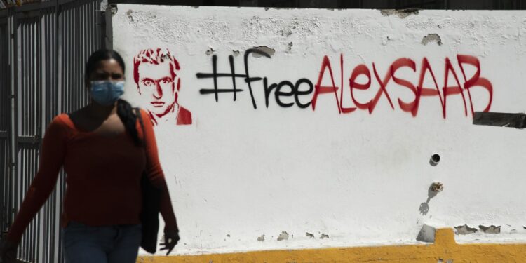A pedestrian passes in front of “Free Alex Saab” graffiti “ in Caracas, on Feb. 4. Photographer: Carlos Becerra/Bloomberg