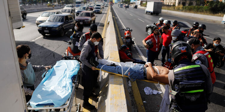 Angels of the Road volunteer paramedics move a person injured in a motorcycle accident on a scoop stretcher into their single ambulance, in Caracas, Venezuela, Wednesday, Feb. 10, 2021. The volunteer paramedics say they feed off the adrenaline of each emergency call. (AP Photo/Ariana Cubillos)