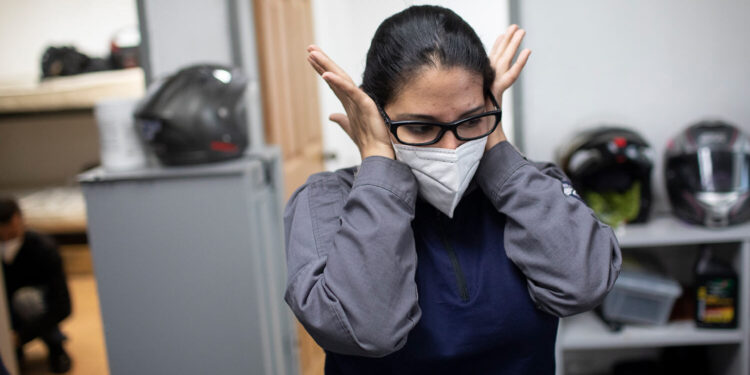 Wearing a mask as a precaution against the new coronavirus, Angels of the Road volunteer paramedic Zully Rodiz rubs her face at the end of her shift at the group's operations base in Caracas, Venezuela, Monday, Feb. 8, 2021. The self-sufficient volunteers seek their own funding and operate entirely independently from the government. (AP Photo/Ariana Cubillos)