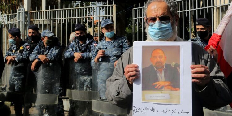 An anti-government activist holds a picture of assassinated Lebanese prominent Shiite Muslim intellectual and Lukman Sleim on Thursday. The 58-year-old was shot four times in the head near the village of Addousiyeh in southern Lebanon, which is mainly controlled by Hezbollah. Photo: Marwan Naamani/dpa