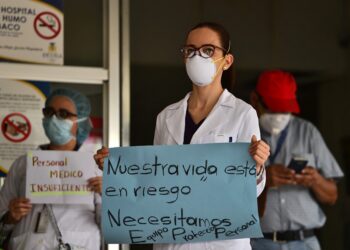 A doctor holds a sign reading "Our Lives are in Danger, We Need PPE" as doctors and nurses of the School Hospital protest against their working conditions and demand personal protective equipment to prevent being infected by the novel coronavirus COVID-19, in Tegucigalpa on April 13, 2020. - The novel coronavirus is 10 times more deadly than swine flu, which caused a global pandemic in 2009, the World Health Organization said Monday, stressing a vaccine would be necessary to fully halt transmission. (Photo by Orlando SIERRA / AFP)