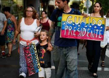 Un migrante venezolano porta un cartel en apoyo a Juan Guaidó en Montevideo, Uruguay, el 7 de febrero de 2019. Foto AP