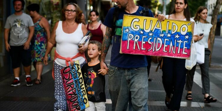 Un migrante venezolano porta un cartel en apoyo a Juan Guaidó en Montevideo, Uruguay, el 7 de febrero de 2019. Foto AP