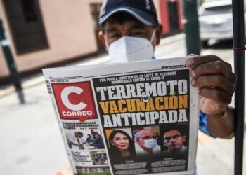 Un hombre muestra un periódico que destaca el escándalo de "vacunación temprana" que involucró a políticos y altos funcionarios, en medio de la pandemia del Covid-19, en Lima, el 15 de febrero de 2021. © AFP
