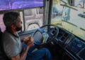 A bus driver counts Bolivar bills while driving on an intercity tour bus in Caracas on January 29, 2021. - Transport is the only sector that still uses Bolivar bills in cash, turning buses into exchange bureaus in poor areas. (Photo by Federico PARRA / AFP)