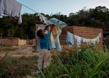 ACOMPAÑA CRÓNICA VENEZUELA POBREZA***AME6198. CARACAS (VENEZUELA), 17/02/2021.- Un niño tiende una sábana frente a su casa de bahareque, el 09 de febrero de 2021, en el sector Las Piedras de San Isidro en Caracas (Venezuela). Tierra, agua, palos de bambú, tablas y zinc es lo que se necesita para construir una vivienda, paradójicamente, más segura en Venezuela. Entre estas paredes y en condiciones muy precarias viven decenas de familias en el barrio San Isidro, ubicado en el este de Caracas, tras huir de la violencia en Güiria, su pueblo natal, en el noreste del país. EFE/ Rayner Peña R.